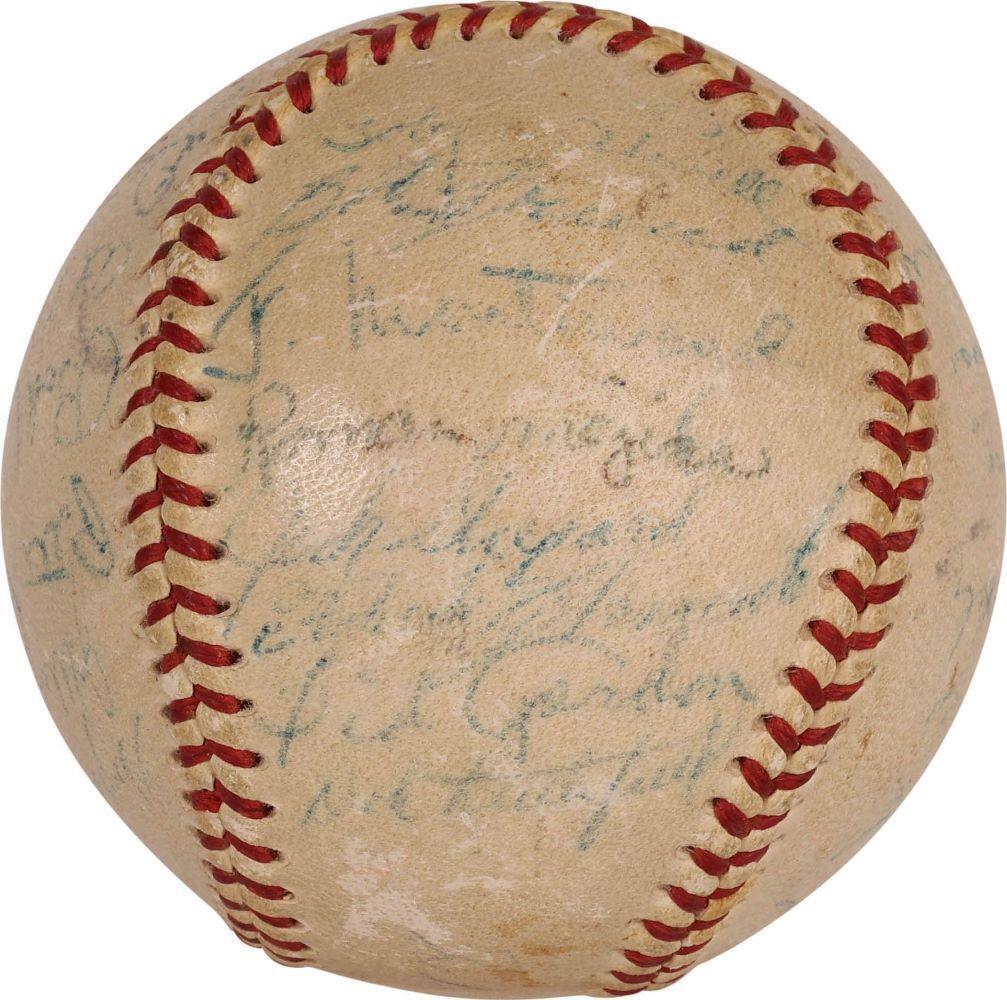 A close-up of a vintage Robert Clemente Rookie Signed 1955 Pirates NL Baseball by Sports Integrity, featuring red stitching and 27 additional faded blue ink signatures; the autographs are worn and hard to decipher.