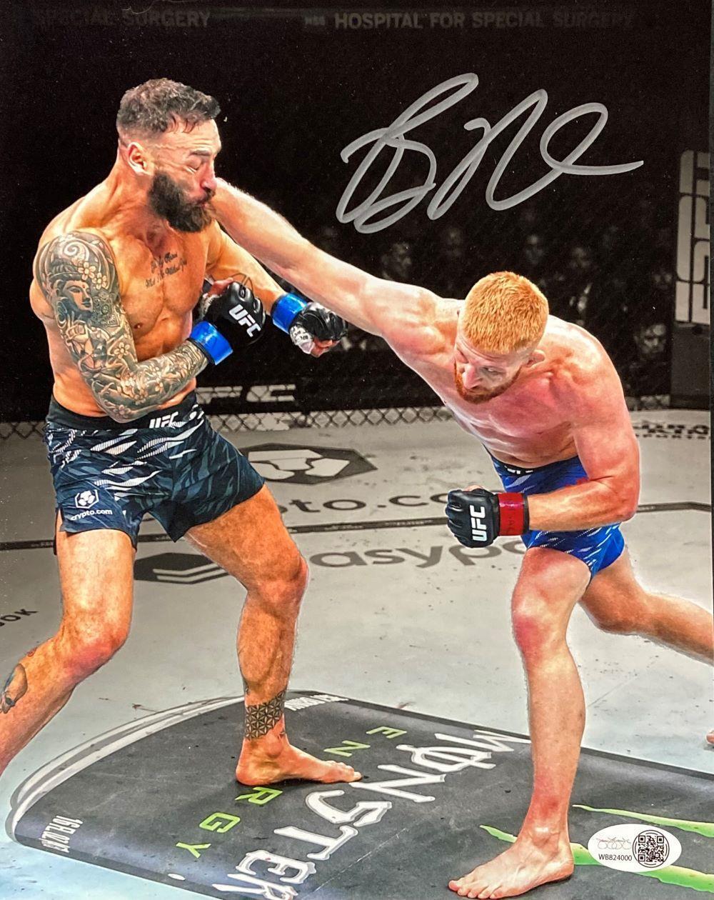 In this Sports Integrity product, Bo Nickal, wearing blue shorts, lands a punch on his bearded opponent in black shorts during a UFC fight. The 8x10 photo features Bo Nickal's signature at the top and includes JSA ITP authentication.