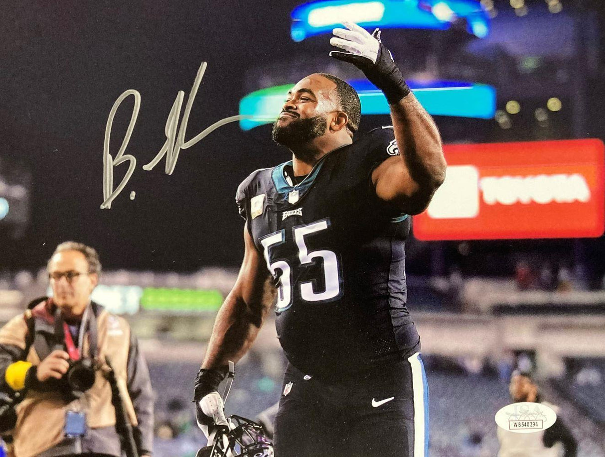 Brandon Graham, #55 of the Eagles in a black jersey, celebrates on the field holding his helmet in this signed 8x10 photo. Authenticated by JSA and offered by Sports Integrity, stadium lights and a photographer are visible in the background.