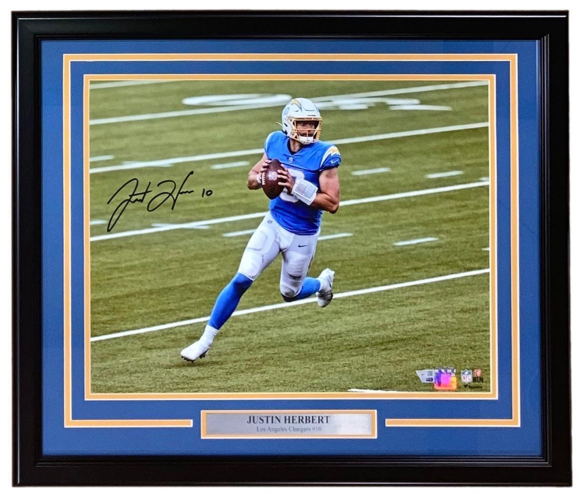 The Sports Integrity Justin Herbert Signed Framed 16x20 Los Angeles Chargers Running Photo features Herbert in a blue uniform with his autograph and a plaque, perfect for Chargers fans.