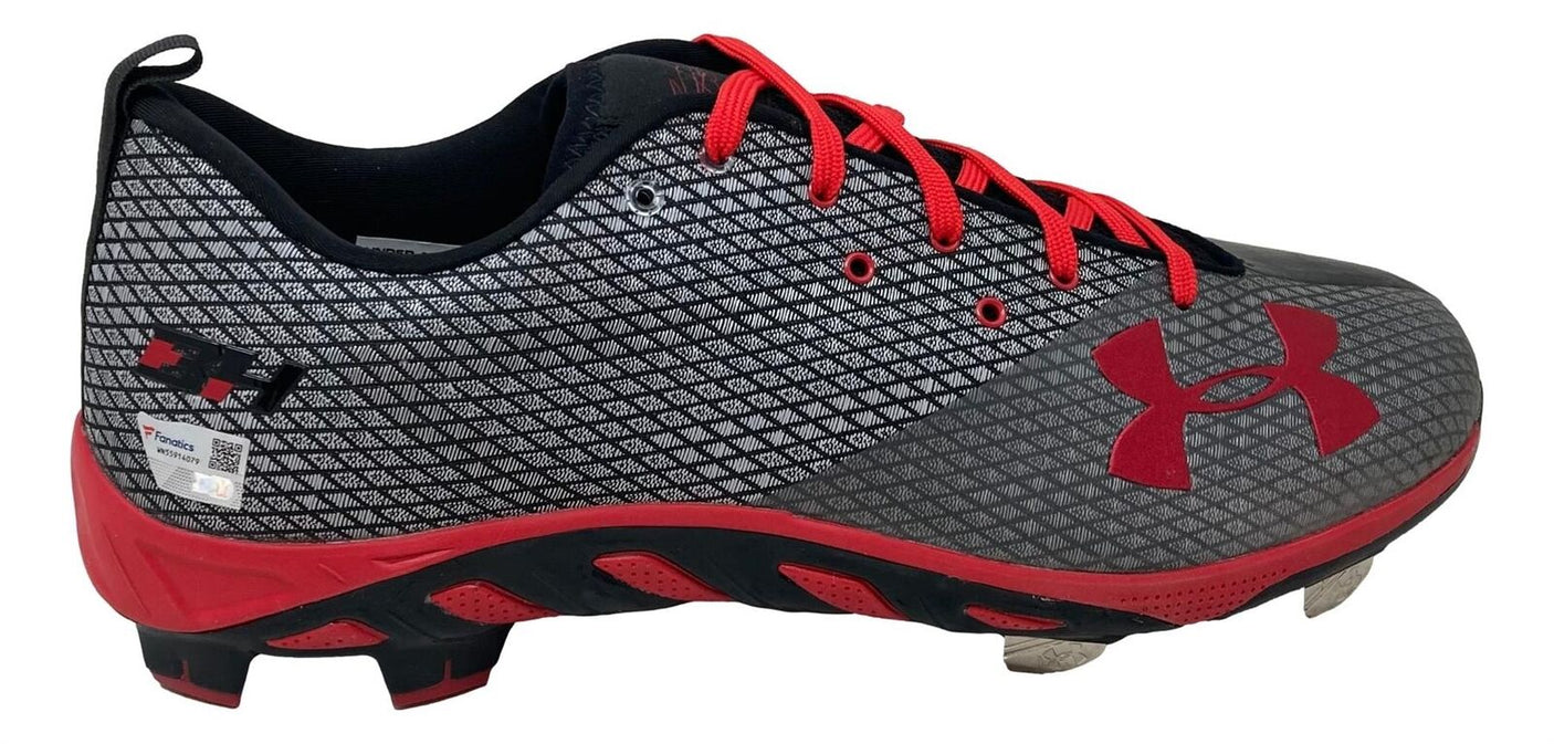 A pair of gray and black Bryce Harper signed Phillies Under Armour cleats by Sports Integrity, featuring a red sole, red laces, red Under Armour logo, and metal studs for traction.