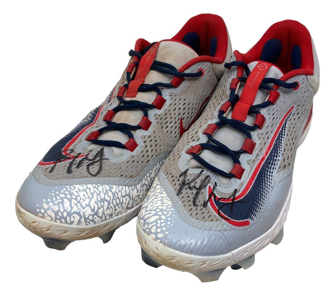 A pair of Paul Goldschmidt twice signed 2023 game-used Cardinals Nike cleats by Sports Integrity, featuring gray and red colors, dark blue accents, visible autographs on the toes, molded studs, and signs of use.