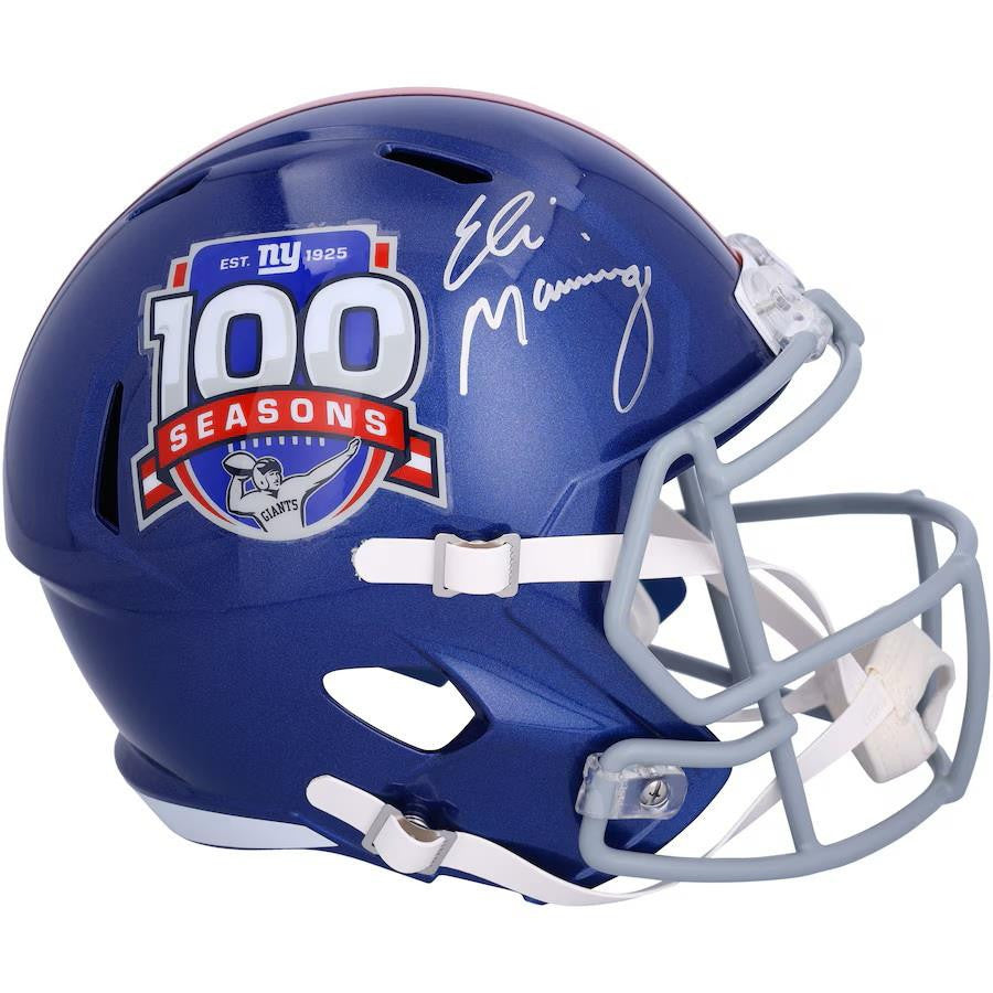This Sports Integrity Eli Manning Signed New York Giants FS 100 Year Speed Replica Helmet features a blue shell, silver facemask, 100 Seasons logo, and Eli Manning’s white ink autograph above the logo.