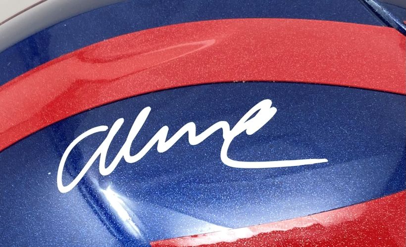A close-up of the Abdul Carter Signed Giants Full Size Alternate Authentic SpeedFlex Helmet by Sports Integrity, featuring a white autograph across its glossy, blue and red surface.