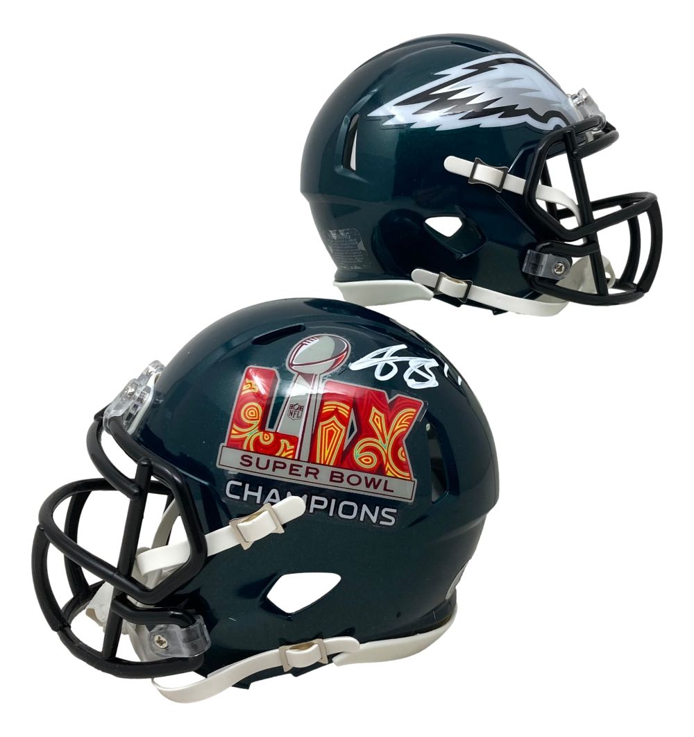 Two dark green AJ Brown signed Philadelphia Eagles Super Bowl 59 Mini Speed Helmets by Sports Integrity, both with black face masks; one shows a silver eagle wing decal, the other features a “Super Bowl Champions” logo and white autograph.