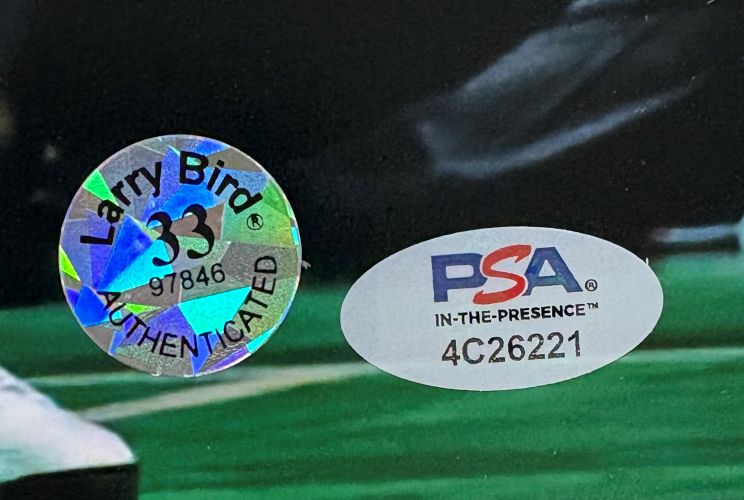 The Larry Bird Signed 16x20 Boston Celtics Photo w/ Michael Jordan (Sports Integrity) features two authentication stickers: a holographic "Larry Bird 33 AUTHENTICATED 97846" and a white oval "PSA IN-THE-PRESENCE 4C26221" on a dark background.