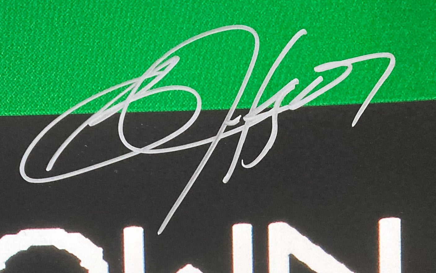 A close-up of Bo Jackson's silver autograph on a 16x20 Oakland Raiders Tecmo Bowl photo by Sports Integrity, with green, black, and partially visible white background and text below the signature.
