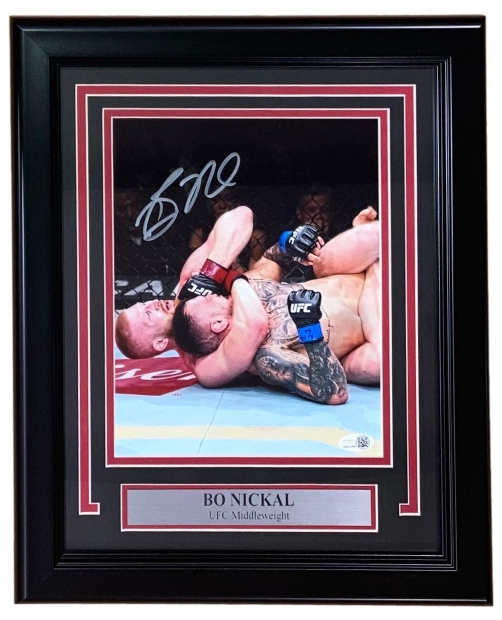 The Sports Integrity Bo Nickal Signed Framed 8x10 UFC Choke Photo (JSA ITP) features Nickal applying a chokehold, his signature at the top, and a nameplate reading “BO NICKAL UFC Middleweight” at the bottom.