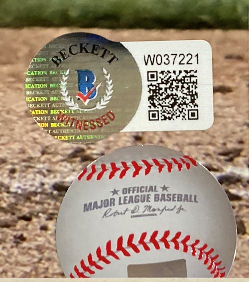 Close-up of a Beckett authentication sticker with QR code on a Bobby Witt Jr signed, framed 16x20 Kansas City Royals photo by Sports Integrity, shown against a blurred field background.
