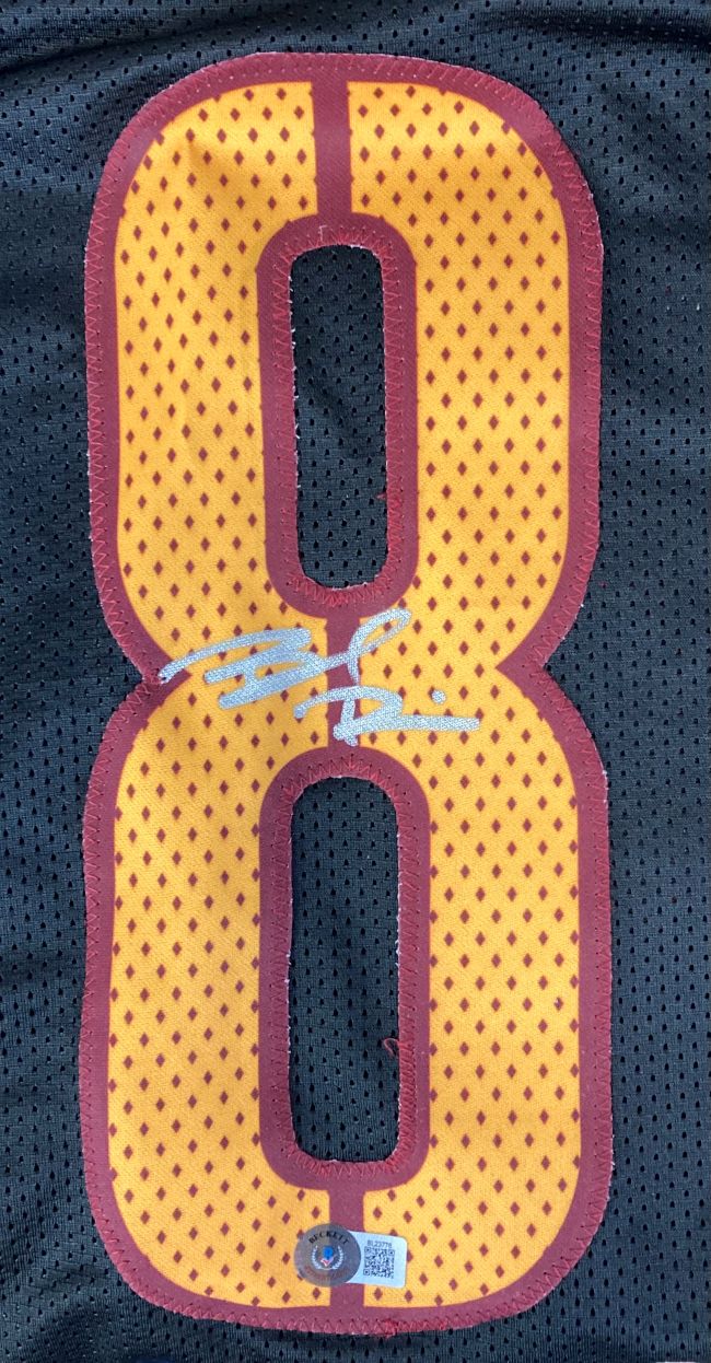 This Brian Robinson Jr Washington Signed Black Alternate Football Jersey by Sports Integrity features a large yellow number eight with red outline, white autograph across the middle, and authenticity sticker at the bottom.