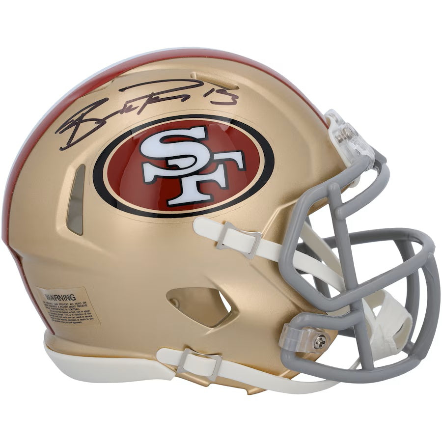 The Brock Purdy Signed San Francisco 49ers Mini Speed Helmet by Sports Integrity features a gold and red design with a gray faceguard, team logo, and Brock Purdy's autograph in black on the top.