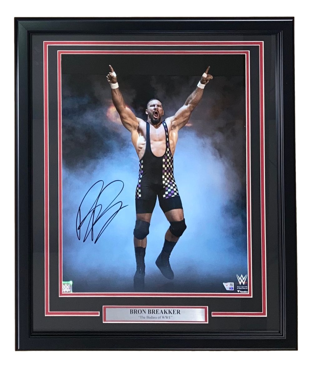 This Sports Integrity Bron Breakker Signed Framed 16x20 WWE Photo by Fanatics features the wrestler in a triumphant pose, wearing a black patterned singlet, with an autographed plaque.