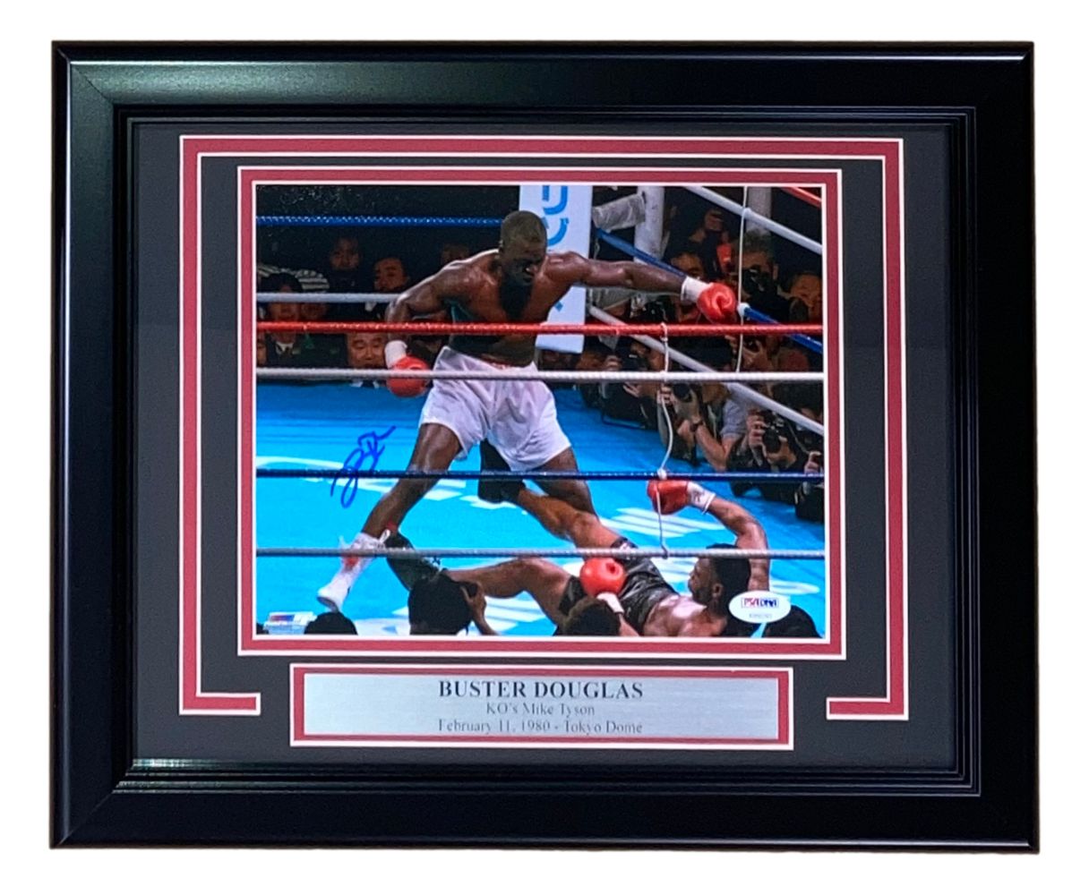 The Sports Integrity Buster Douglas Signed Framed 8x10 Photo shows Douglas standing over Mike Tyson after his knockout on February 11, 1990, at Tokyo Dome. Includes PSA/DNA authentication and commemorative plaque.
