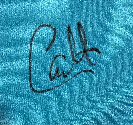 A black autograph-style "Catt" signature appears on shiny blue fabric of Sports Integrity’s Carlito Signed Custom Wrestling Shorts, authenticated by a JSA QR hologram.