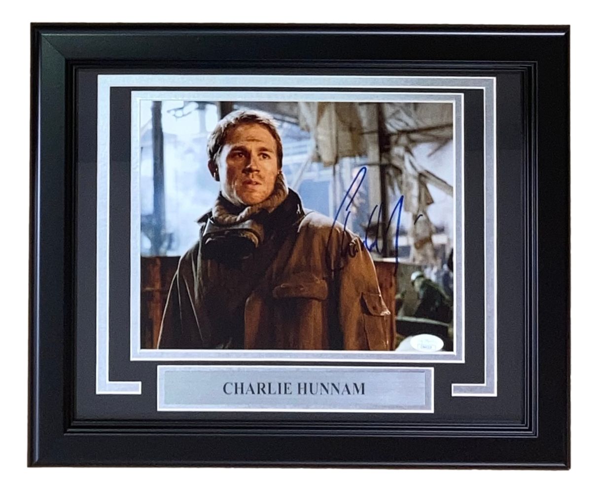 The Sports Integrity Charlie Hunnam Signed Framed 8x10 Pacific Rim Photo (JSA) features an autograph and a nameplate, showing Hunnam in outdoor gear in front of an industrial background, looking to the side.