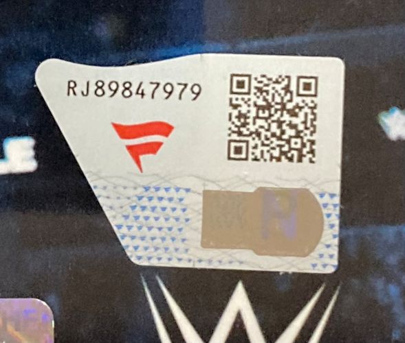 A close-up of a Sports Integrity sticker with code RJ89847979, a red F logo, QR code, and hologram, on the Charlotte Flair Signed Framed 8x10 WWE 2025 Royal Rumble Photo by Fanatics, with a blurred WWE logo in the background.