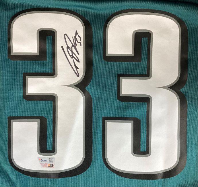 Close-up of a Cooper DeJean Signed Philadelphia Eagles Green Nike Game Jersey by Sports Integrity, showing the large white number 33 outlined in black with autograph and two authentication stickers near the bottom left digit.