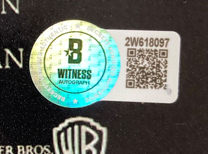A close-up of the Beckett Witness Authentication sticker with hologram, QR code, and serial 2W618097 on a Corey Feldman Signed 11x17 The Lost Boys Photo Love Inscribed by Sports Integrity.