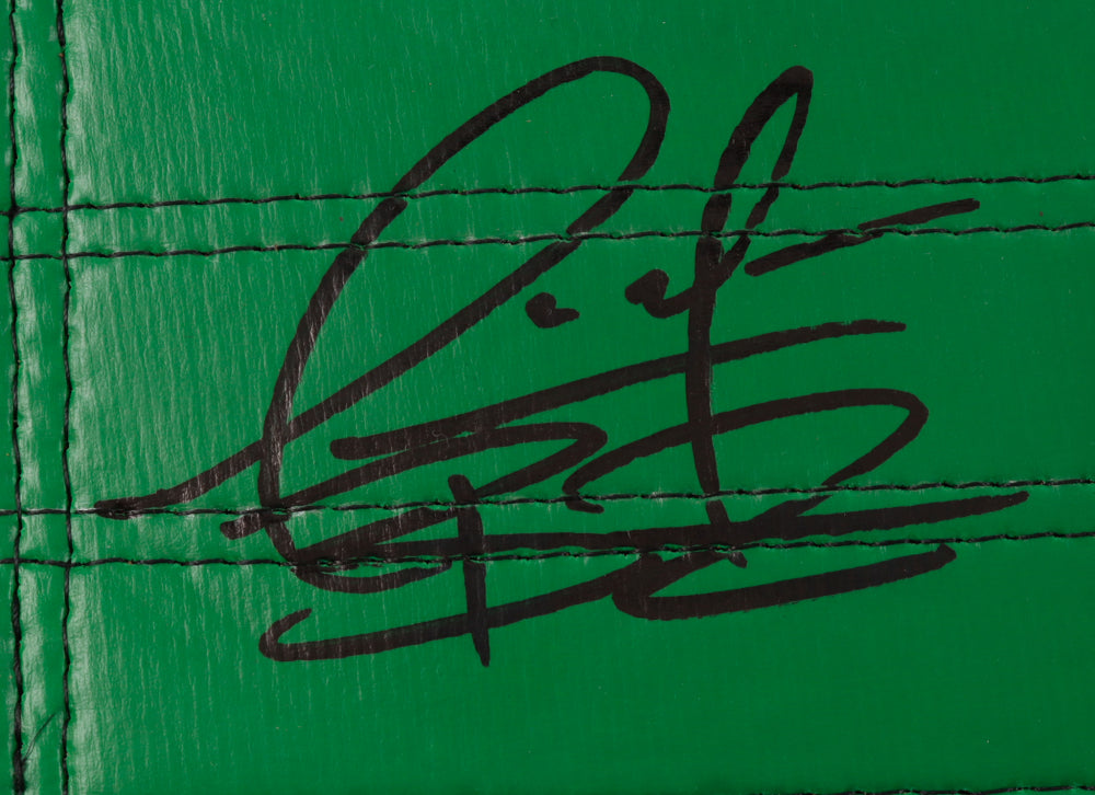 A close-up of Deontay Wilder's black autograph on a green textured, stitched surface of a Sports Integrity Full Size Replica Boxing Championship Belt.