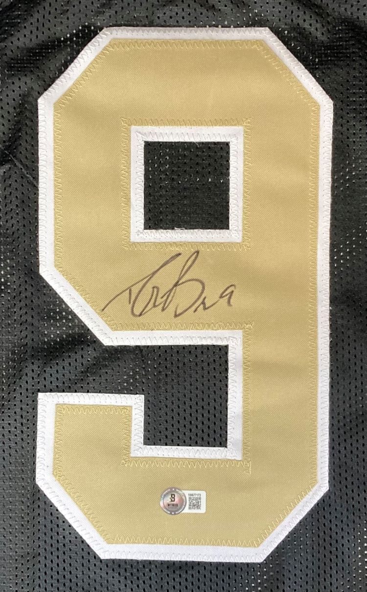 A gold and white number 9 is sewn onto black mesh fabric on this Drew Brees New Orleans Signed Black Football Jersey by Sports Integrity, featuring his signature in black ink and an authentication sticker at the bottom.