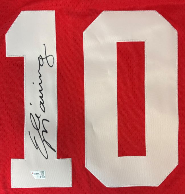 Eli Manning Signed New York Giants M&N 2004 Red Legacy Jersey by Sports Integrity features a large white number 10 with his autograph in black ink across the number and an authentication sticker on the lower part of the "1".