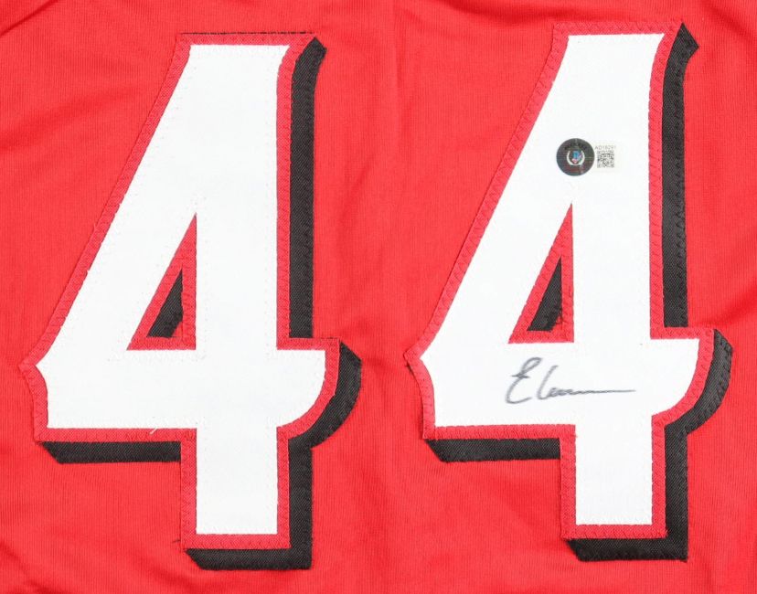 A close-up of the Elly De La Cruz Cincinnati Signed Red La Cocoa Baseball Jersey by Sports Integrity shows large white 44 numbers outlined in black, with a sticker and signature under one number.