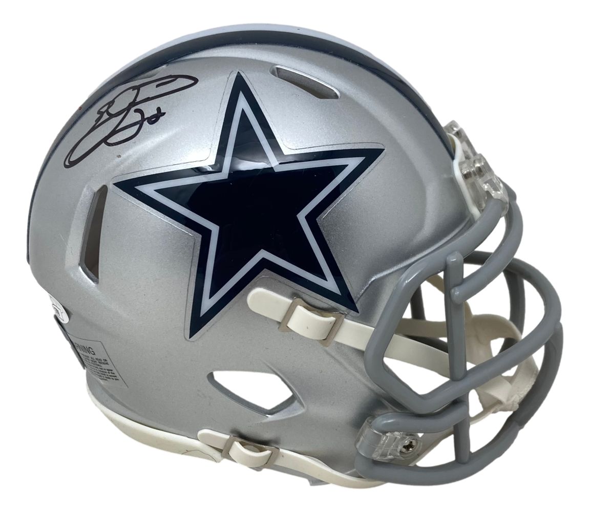 The Sports Integrity Emmitt Smith Signed Dallas Cowboys Mini Speed Replica Helmet features a silver finish, navy blue star with white outline, gray facemask, and Emmitt Smith’s black signature above the logo. JSA certified.
