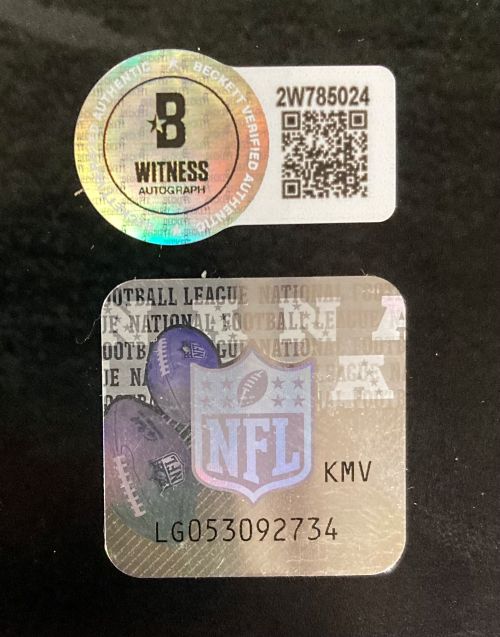A close-up of authentication stickers on the Sports Integrity B Graham M Williams Signed 16x20 Eagles Super Bowl Strip Sack Collage Photo BAS, showing a Beckett Witness Autograph hologram with QR code and an NFL logo sticker with code LG053092734.