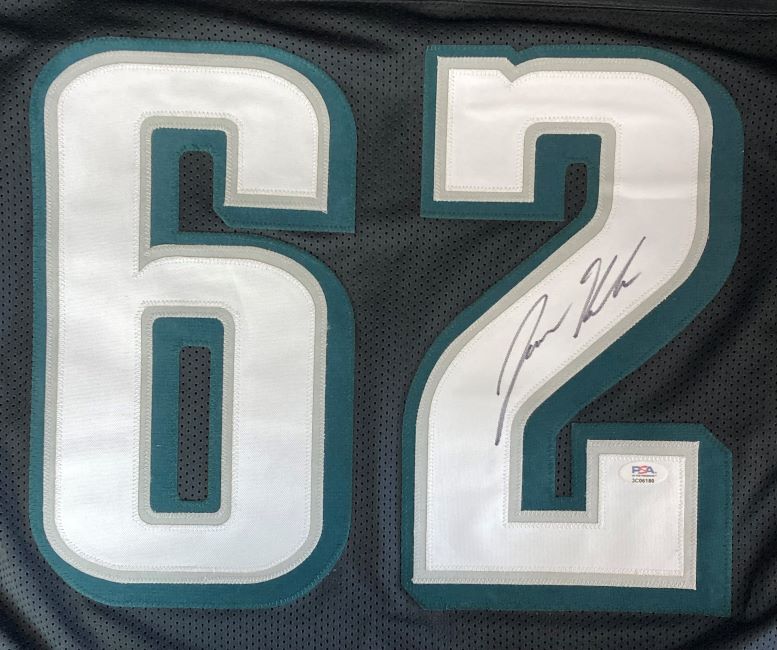 A close-up of a Jason Kelce Philadelphia Signed Black Football Jersey by Sports Integrity shows the large white number 62 with teal outline, Kelce’s signature in black ink on the 2, and a PSA ITP hologram for authentication.