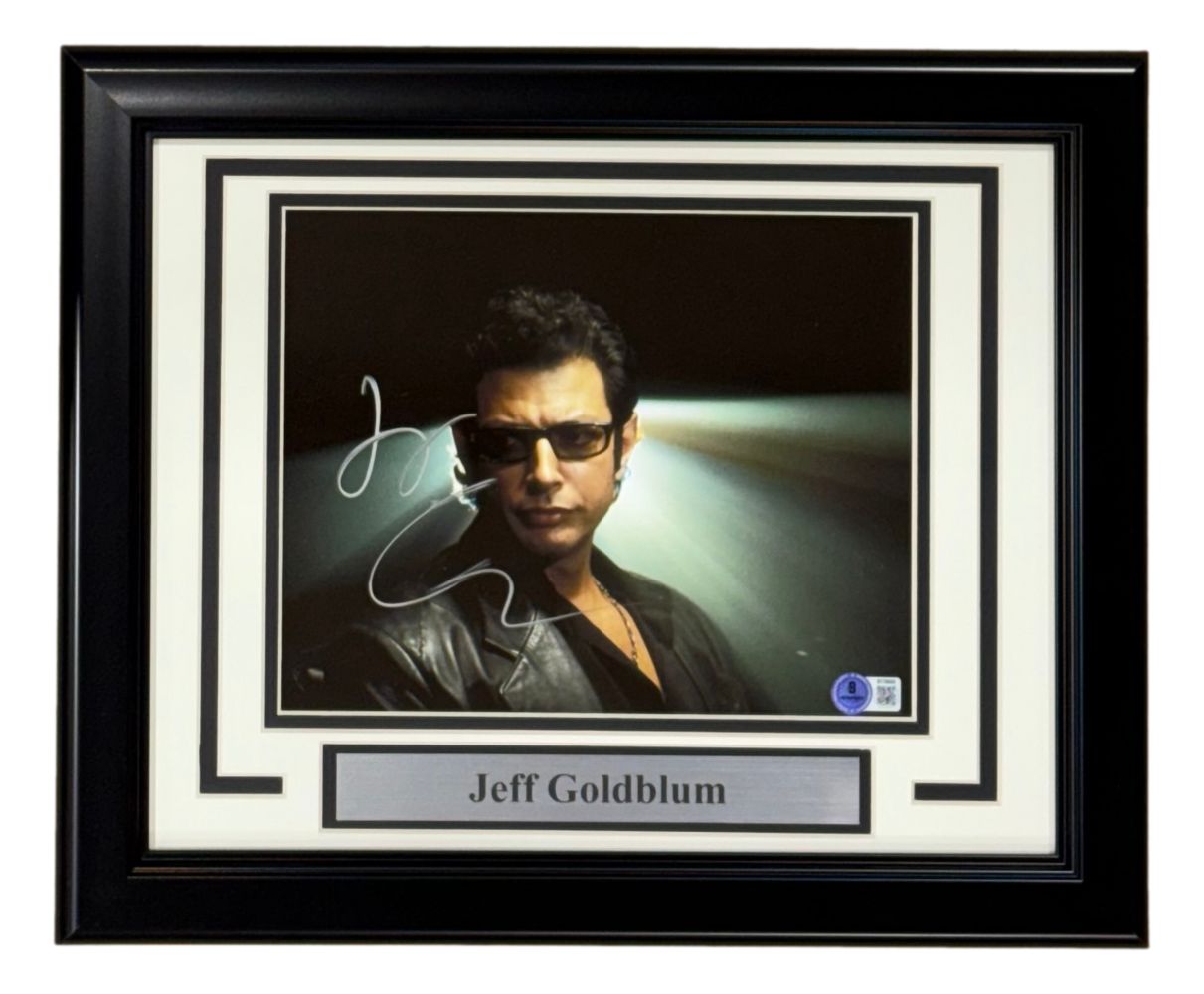 A Sports Integrity framed 8x10 photo of Jeff Goldblum from Jurassic Park, signed and authenticated by BAS, features him in sunglasses and a black leather jacket with dramatic lighting.
