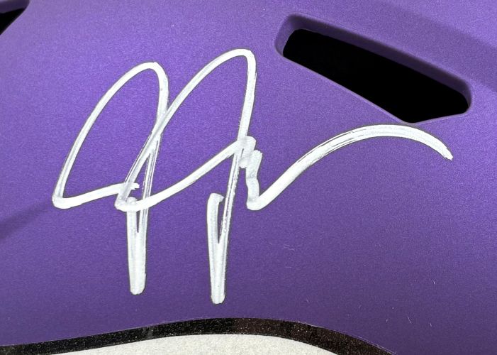 A white autograph is inscribed on the smooth, purple surface of a Justin Jefferson Signed Minnesota Vikings FS Replica Speed Helmet by Sports Integrity, with black vent openings visible above the signature.