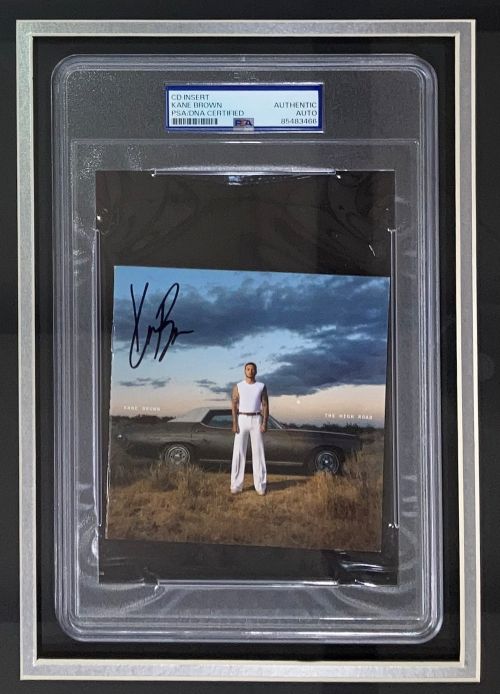Sports Integrity Kane Brown Signed Framed "The High Road" CD Booklet with 11x14 Photo, PSA certified, featuring Kane Brown in front of a car on a field under a cloudy sky.