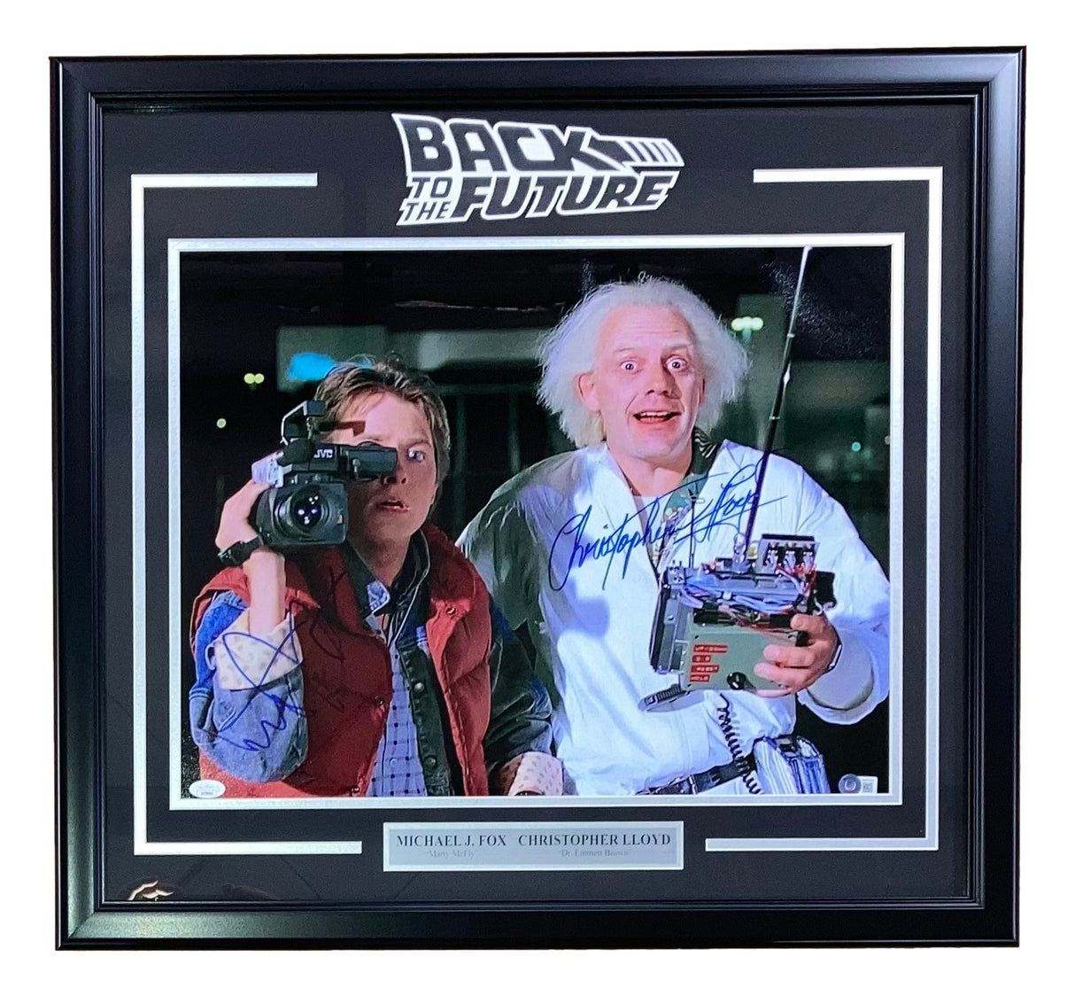 The Sports Integrity Michael J Fox & Lloyd Signed Framed 16x20 Back to the Future Camera Photo BASJSA shows both stars with visible autographs—one in a red vest with a camera, the other in a lab coat holding a remote.