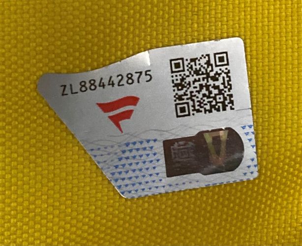 A silver sticker with a QR code, serial number ZL88442875, a red F logo, and blue patterns is on the 148th Open Championship Royal Portrush PGA Event Issued Golf Pin Flag by Sports Integrity.