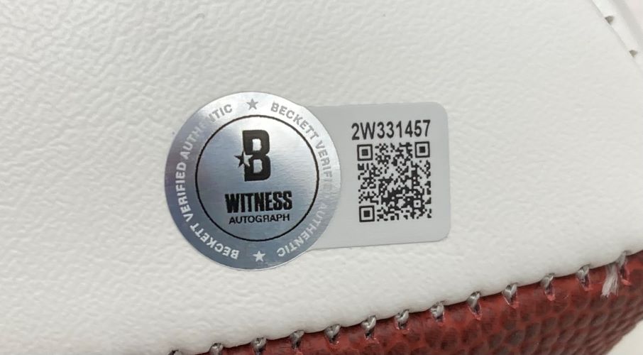 A close-up of a Beckett Witness Autograph sticker and QR code on a Randall Cunningham Signed Philadelphia Eagles Logo Football by Sports Integrity, displayed with its included case.