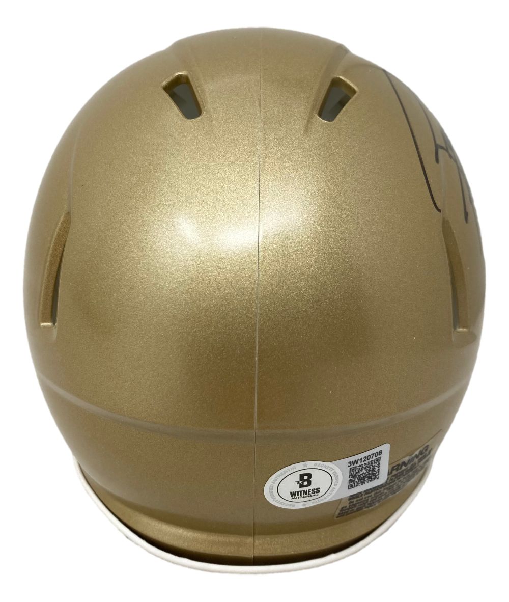 A Rudy Ruettiger Signed Notre Dame Mini Speed Helmet by Sports Integrity, seen from the back with ventilation slots, a barcode sticker, and a certification label featuring the Witmer logo.