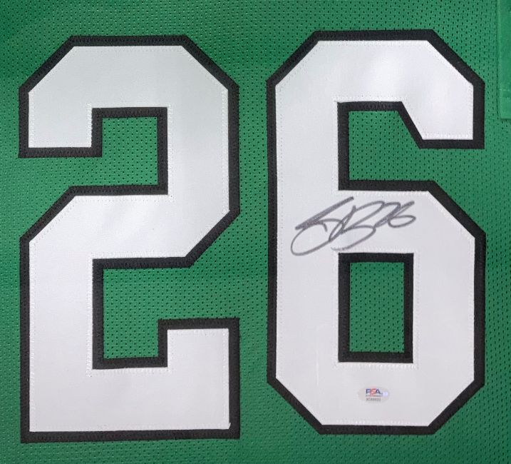 The Sports Integrity Saquon Barkley Philadelphia Kelly Green football jersey features white numbers "26" outlined in black, a black marker signature on the "6," an authentication sticker below, and comes signed and framed with PSA/DNA certification.