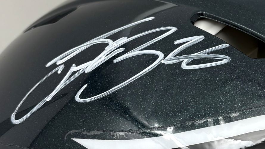 A close-up of the Sports Integrity Saquon Barkley Signed Philadelphia Eagles FS Authentic Speed Helmet, showcasing his bold silver autograph across the dark surface.