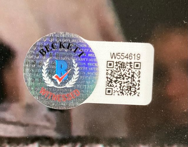 Close-up of a Beckett Witnessed sticker with holographic seal and white QR label (code W554619) on a Stone Cold Steve Austin WWE WWF Signed 16x20 Photo by Sports Integrity.