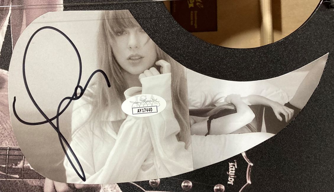 A black & white Taylor Swift Kiss Graphic Acoustic Guitar (41") by Sports Integrity, featuring Taylor’s large black signature and JSA AY37440 sticker.