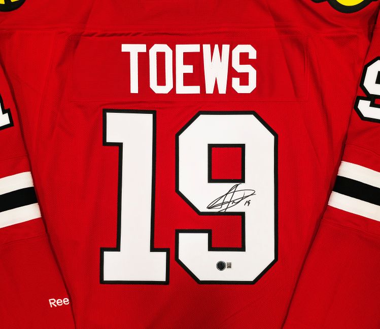 The Sports Integrity Jonathan Toews Signed Chicago Blackhawks Reebok Premier Hockey Jersey features TOEWS and #19 with a signature on the 9, plus black, white, and yellow shoulder patches.