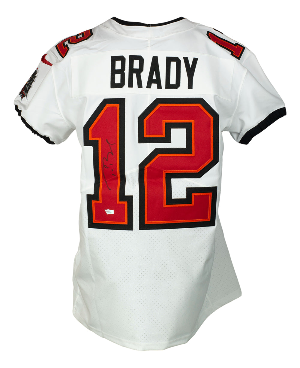 A Tom Brady Tampa Bay Buccaneers Nike Elite football jersey by Sports Integrity, white with black and red accents, features "BRADY" and signed #12 on the back.