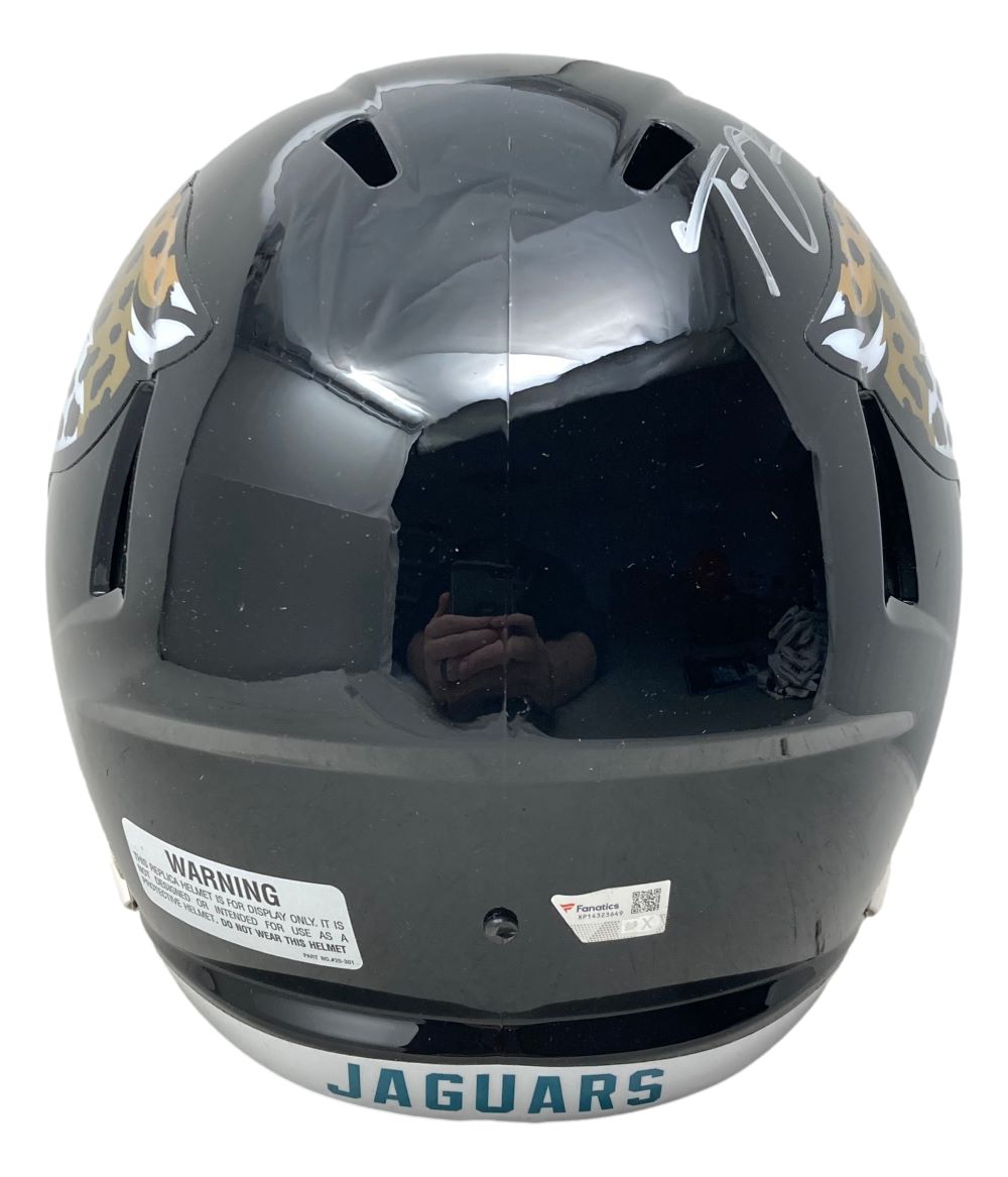 The Trevor Lawrence Signed Jaguars Full Size Replica Speed Helmet by Sports Integrity displays JAGUARS on the back, jaguar graphics on each side, a warning label, and a white autograph on the upper right—all encased with a Fanatics case.