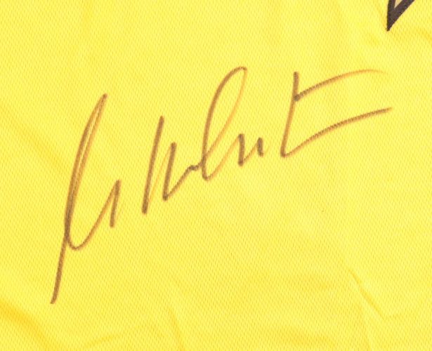 A William Shatner autograph appears in black ink on a yellow Star Trek Captain Kirk costume shirt by Sports Integrity, authenticated by JSA. The signature is stylized and not clearly legible.