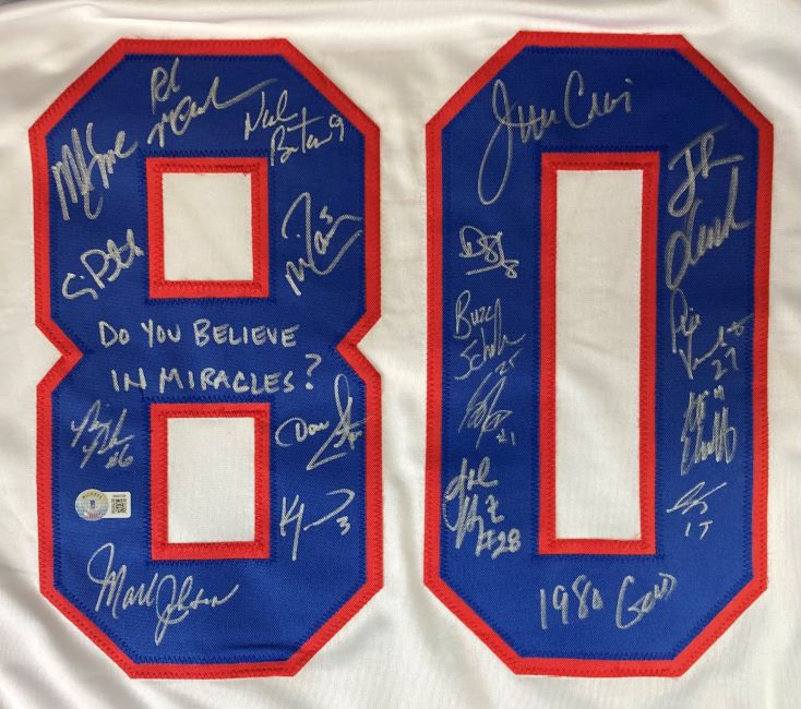 The Sports Integrity 1980 USA Hockey Signed White Olympic Jersey features the blue and red number 80, multiple signatures from 18 players, and "Do you believe in miracles?" written inside the left zero.