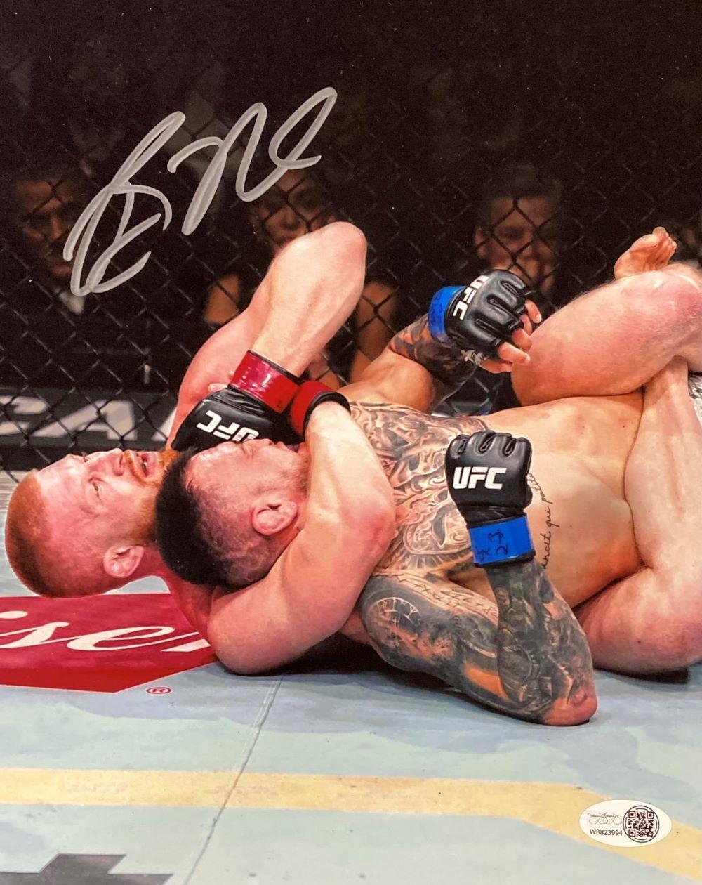 The Sports Integrity Bo Nickal Signed 8x10 UFC Choke Photo (JSA ITP) shows Bo Nickal applying a rear-naked choke in the octagon, both fighters wearing UFC gloves and mouthguards. Image autographed in silver marker.
