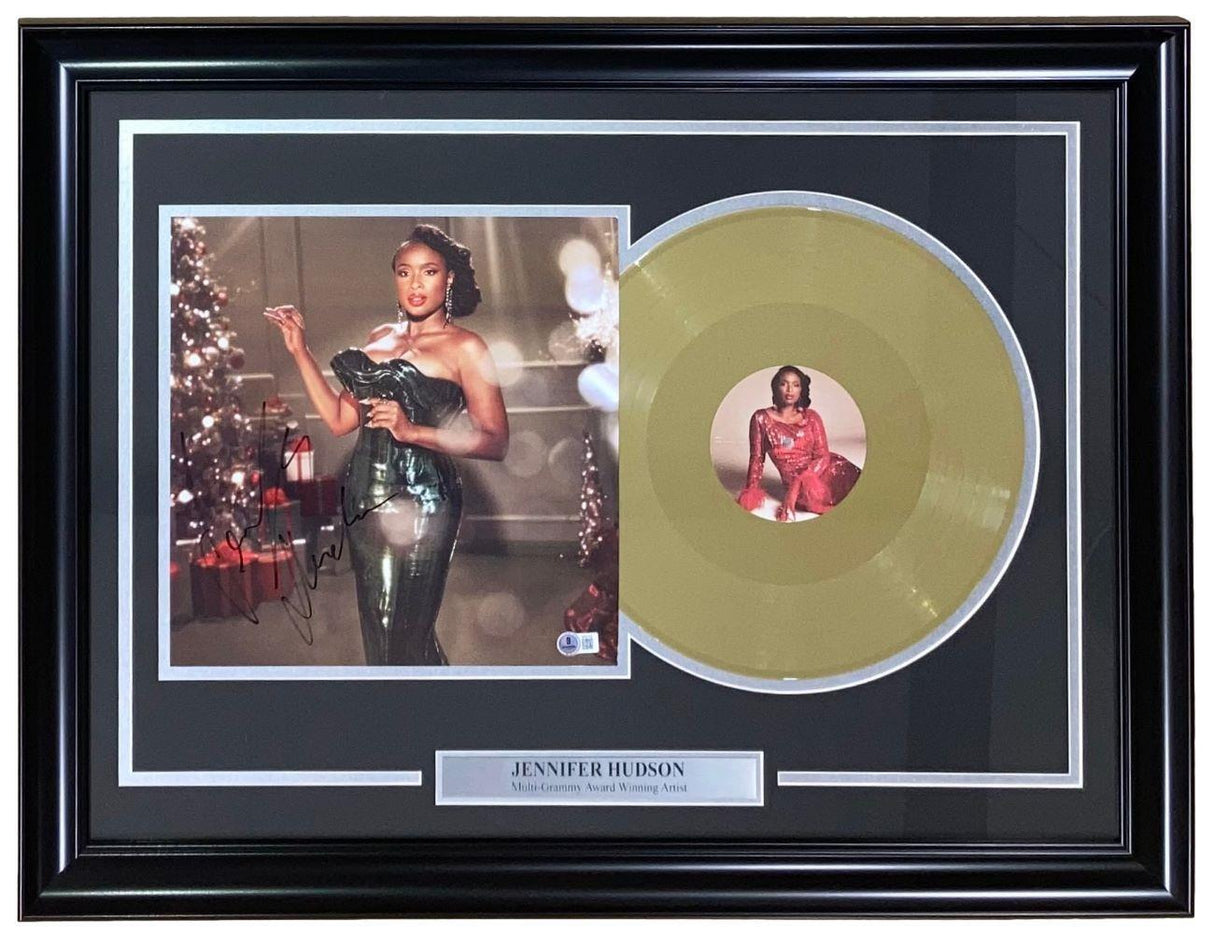 Sports Integrity’s Jennifer Hudson Signed Framed "The Gift Of Love" Vinyl Insert features her photo in a shiny green dress by a Christmas tree, an autographed gold vinyl, and an award nameplate.