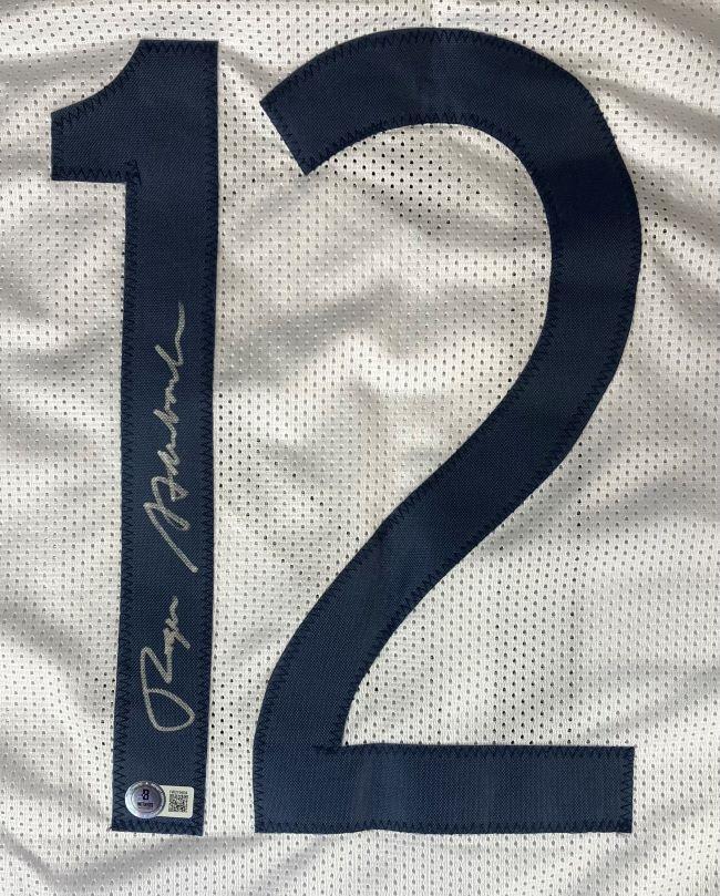 The Sports Integrity Roger Staubach Navy Signed White Football Jersey BAS features a bold dark blue number 12 with a silver autograph on the left and an authentication sticker at the lower left corner.