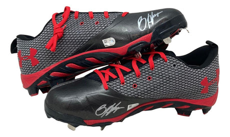 A pair of black and gray Bryce Harper signed game-issued Phillies Under Armour cleats from Sports Integrity, featuring red laces, red accents, and white autographs on the toe of each shoe.