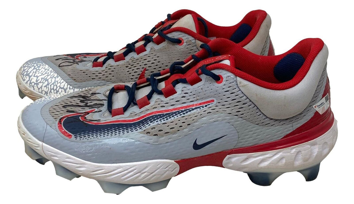 A pair of Paul Goldschmidt Twice Signed 2023 Game Used Cardinals Nike Cleats by Sports Integrity, featuring textured details, molded studs, navy blue laces, and black swoosh logos.